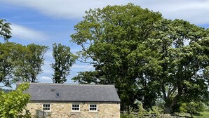 A stone building with a sloped roof, a small window, and a door. - Romantic 1 bedroom Rural Retreat with spectacular views across Northumberland (Hexham)