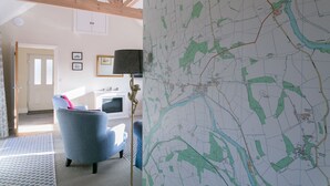 A room with a map, a blue armchair, a lamp, and a fireplace. - Romantic 1 bedroom Rural Retreat with spectacular views across Northumberland (Hexham)