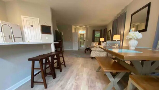 A spacious kitchen with wooden bar stools, a dining table, and a refrigerator. - Bluffton Retreat, Pet Friendly (Bluffton)