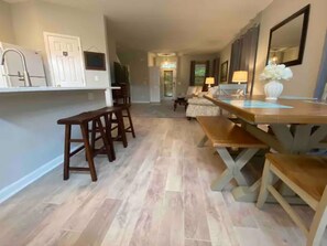 A spacious kitchen with wooden bar stools, a dining table, and a refrigerator. - Bluffton Retreat, Pet Friendly (Bluffton)