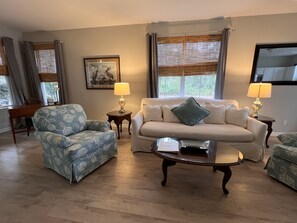A living room with a patterned armchair, a sofa with a pillow, a coffee table, and two lamps. - Bluffton Retreat, Pet Friendly (Bluffton)