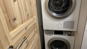 A compact, two-door laundry room with a wooden door and a white washing machine. - Romantic Luxury appartment in the heart of Grachen (Grächen)
