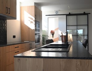 Een moderne keuken met houten kastjes, een roestvrijstalen oven en een zwart aanrecht.