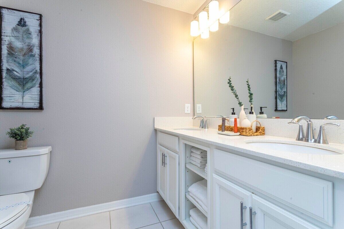 Une salle de bain moderne avec un meuble-lavabo blanc, deux vasques et un grand miroir.