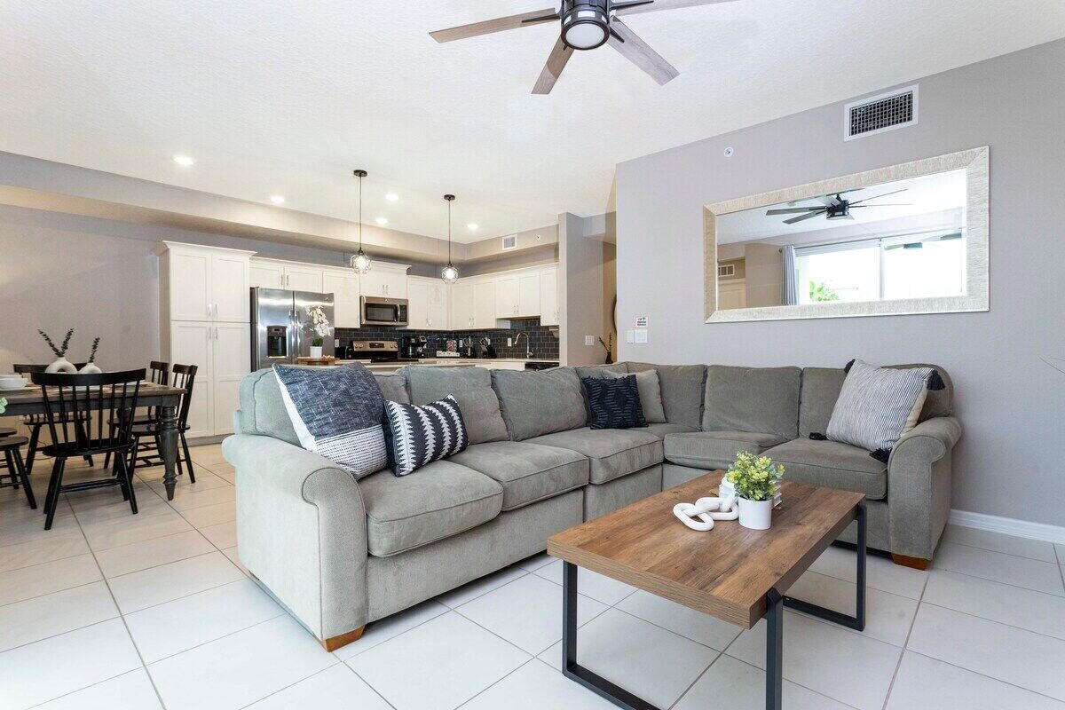 A modern living room with a sectional sofa, a wooden coffee table, and a dining area with a table and chairs.