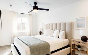 A bedroom with a bed, a ceiling fan, a bedside table with a lamp, and a window with curtains. - Desert Memories: Desert Color Lagoon + Beaches (St. George)
