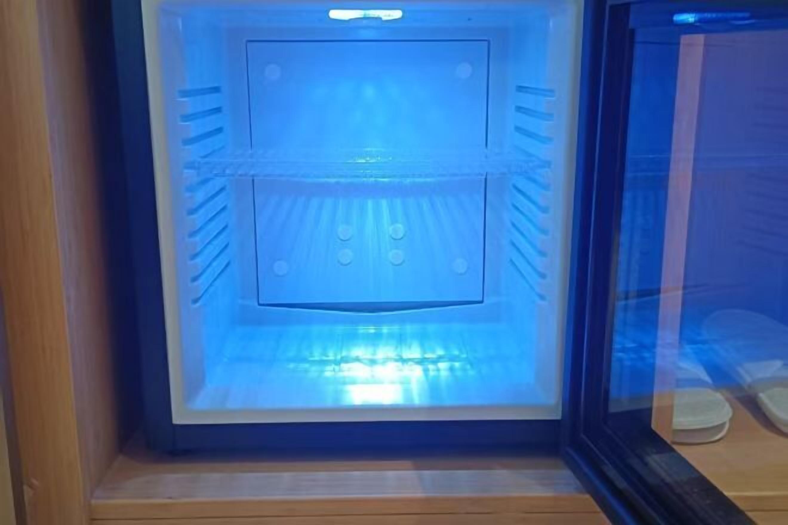 Una habitación con una lámpara azul grande e iluminada, suelo de madera y un panel de vidrio.