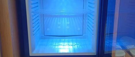 Una habitación con una lámpara azul grande e iluminada, suelo de madera y un panel de vidrio.