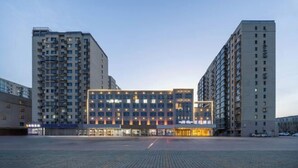 A modern hotel with a central building featuring multiple floors and a flat roof, surrounded by taller residential buildings. - Starway Hotel (Beijing Yanqi Development Zone) (Beijing)