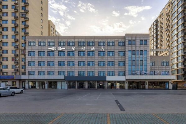 A hotel building with a modern facade, multiple windows, and a parking lot in front. - Starway Hotel (Beijing Yanqi Development Zone) (Beijing)