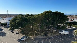 A parking lot with several cars and a white van, surrounded by trees and a clear blue sky. - Lovely flat with beautiful views AV-32 (Roses)