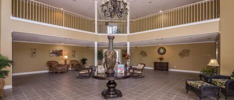 A spacious lobby with a high ceiling, a central chandelier, and a two-story balcony.