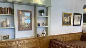 A restaurant interior with wooden paneling, a cushioned booth, and shelves with books and decorative items. - Old Swan (Skipton)
