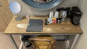 A wooden desk with a laptop, a remote control, a coffee maker, and various toiletries. - Old Swan (Skipton)