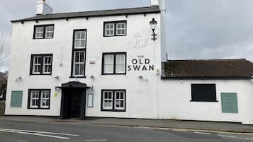 A white building with black-framed windows and a sign reading "The Old Swan."