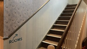 A staircase with a directional arrow pointing to the right, indicating the way to rooms. - Old Swan (Skipton)