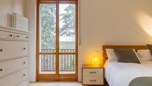 A bedroom with a bed, bedside table with a lamp, a dresser, and a sliding glass door leading to an outdoor area. - Alle mura apartment (Verona)