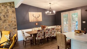 A dining area with a stone wall, a chandelier, and a view through a glass door. - IML -NearJim Thorpe-Pets Allowed🐕‍🦺 Free, Sleeps10 (Albrigthsville)
