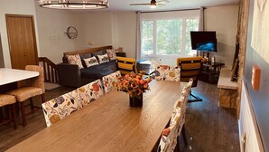 A modern living room with a wooden dining table, a sofa, and a TV. - IML -NearJim Thorpe-Pets Allowed🐕‍🦺 Free, Sleeps10 (Albrigthsville)