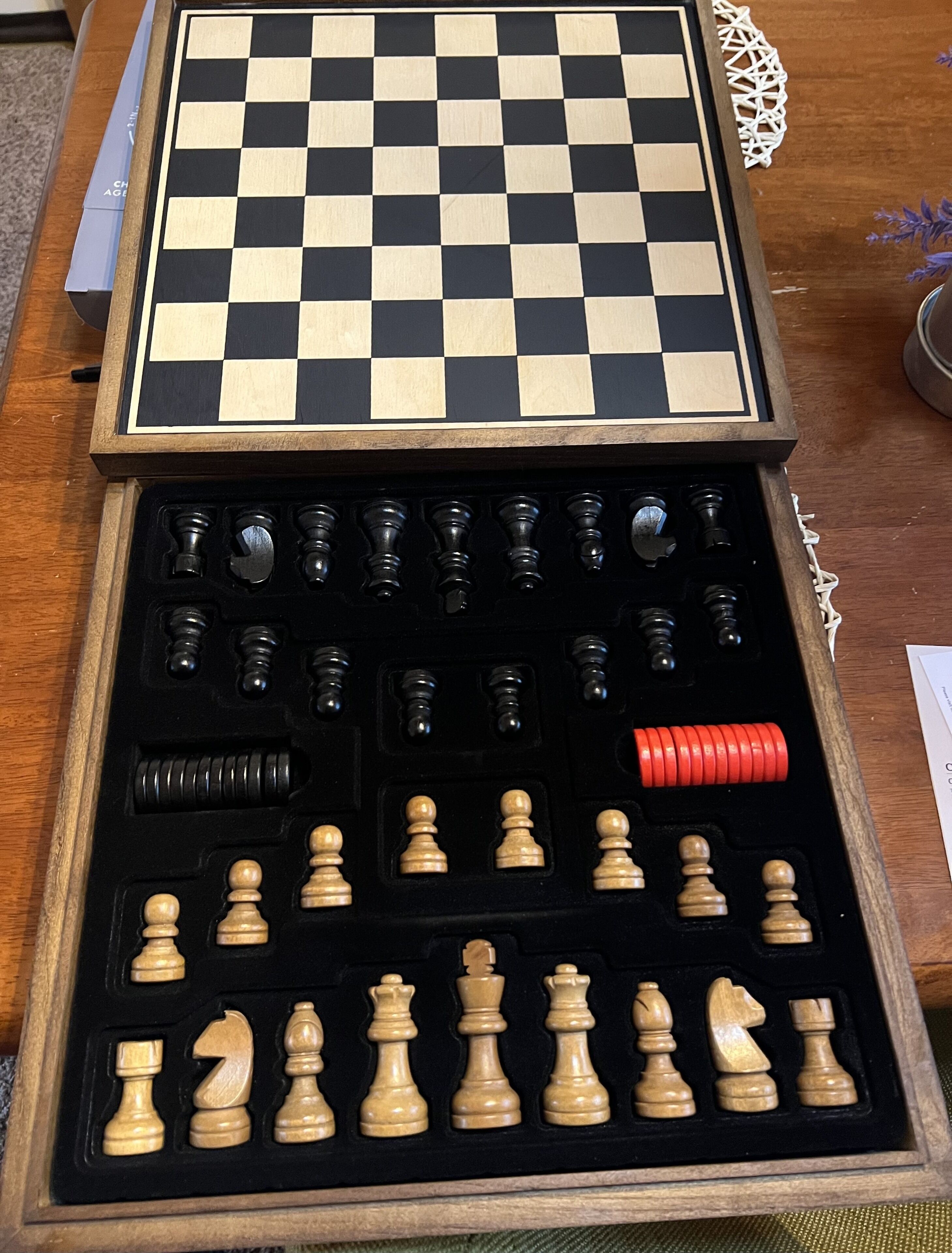 Un jeu d’échecs comprenant un échiquier à carreaux et des pièces rangées dans une boîte en bois.