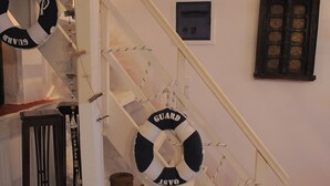 A staircase with lifebuoys hanging from the handrails, a small table with a basket, and a framed picture on the wall. - Dandy Villas Velanidia Sailor's House - Private Maisonette - Sea View (Velanidia)