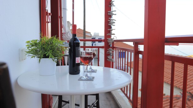 A small round table with a potted plant and a bottle of wine on a balcony. - Dandy Villas Velanidia Sailor's House - Private Maisonette - Sea View (Velanidia)