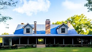 A two-story building with a metal roof, a covered porch, and a brick chimney. - Romantic Suite 500 sq ft. of privacy (Mount Pleasant)