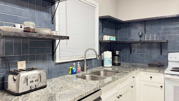 A kitchen with a granite countertop, a toaster, a coffee maker, and a stove. - 2 Bed 2.5 Bath Townhome in Norcross (Gwinnett County) (Norcross)