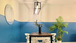 A dining area with a wooden table, white chairs, a black vase with plants, and a mirror on the wall. - 2 Bed 2.5 Bath Townhome in Norcross (Gwinnett County) (Norcross)