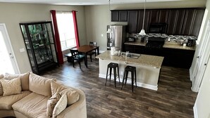 Une cuisine moderne avec des meubles de couleur sombre, un îlot central et un coin repas comprenant une table et des chaises.