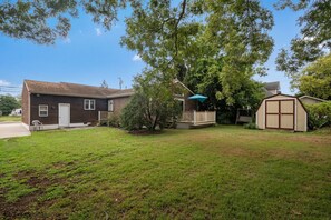 A two-story house with a front porch, a small shed, and a tree in the yard. - Spacious ranch 65” 4K tv deck, grill, fire pit fenced yd , office,  baby gear (Cape May Court House)