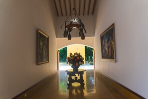 Um corredor com um candelabro, quadros nas paredes e uma mesa com flores no centro.