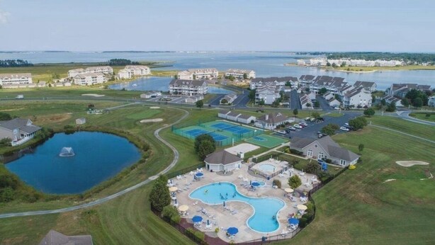 Vue aérienne d’un quartier résidentiel avec de nombreuses maisons, une grande piscine et un lac.