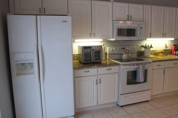 A kitchen with white cabinets, a microwave, a double oven, and a refrigerator.