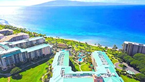 Un resort con varias edificaciones, una zona de piscina central y vistas al océano.