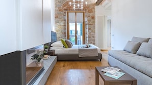 A modern bedroom with a stone wall, a bed, a sofa, and a TV.
