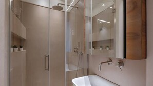 Une salle de bain moderne avec une douche à parois de verre, un lavabo blanc et un miroir.