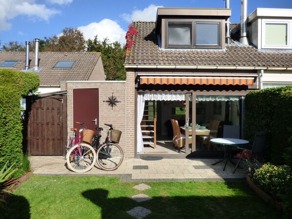 A house with a patio, a wooden door, and two bicycles parked outside.