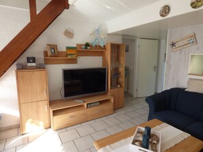 A living room with a TV, wooden furniture, and a blue couch.