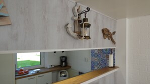 Une cuisine avec une fenêtre, une machine à café et une étagère où sont disposés des objets décoratifs.