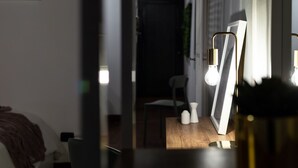 A dimly lit room with a bed, a chair, and a table with a framed picture and salt and pepper shakers. - Wine Apartments Florence Ciliegiolo  (Firenze)