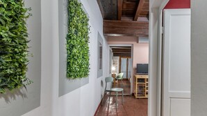 A hallway with a green wall installation, a wooden desk, and chairs. - Wine Apartments Florence Ciliegiolo  (Firenze)