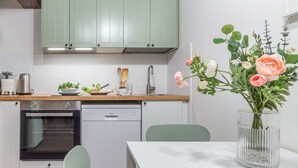 A modern kitchen with green cabinets, a dishwasher, an oven, and a dining area with a table and chairs. - Wine Apartments Florence Ciliegiolo  (Firenze)