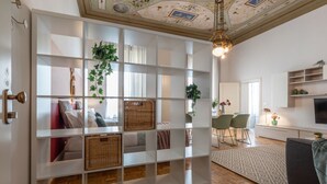A modern living room with a white shelving unit, wicker baskets, and a dining area with chairs and a table.