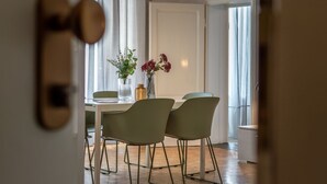 A dining area with a table and chairs, a vase with flowers, and a door with a handle.