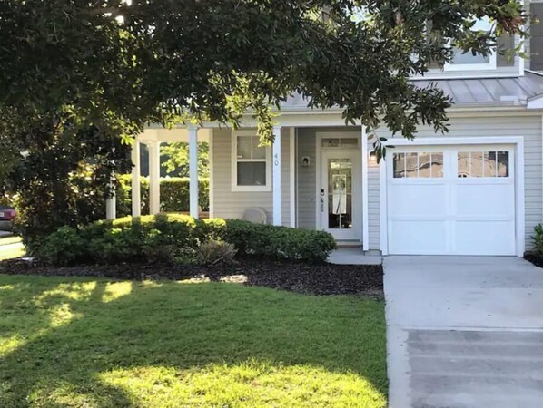 A two-story house with a front porch, a garage, and a well-maintained lawn.