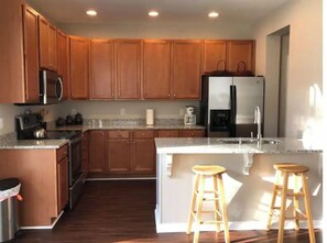 A modern kitchen with wooden cabinets, stainless steel appliances, and a large island with stools.