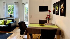Una sala de estar moderna con sofá, mesa de comedor y vistas al exterior a través de una ventana.