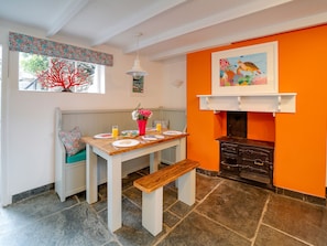 A dining area with a wooden table, bench, and orange walls.