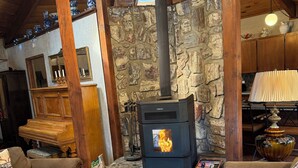 Una sala de estar acogedora con una pared de piedra, muebles de madera y una estufa de leña.
